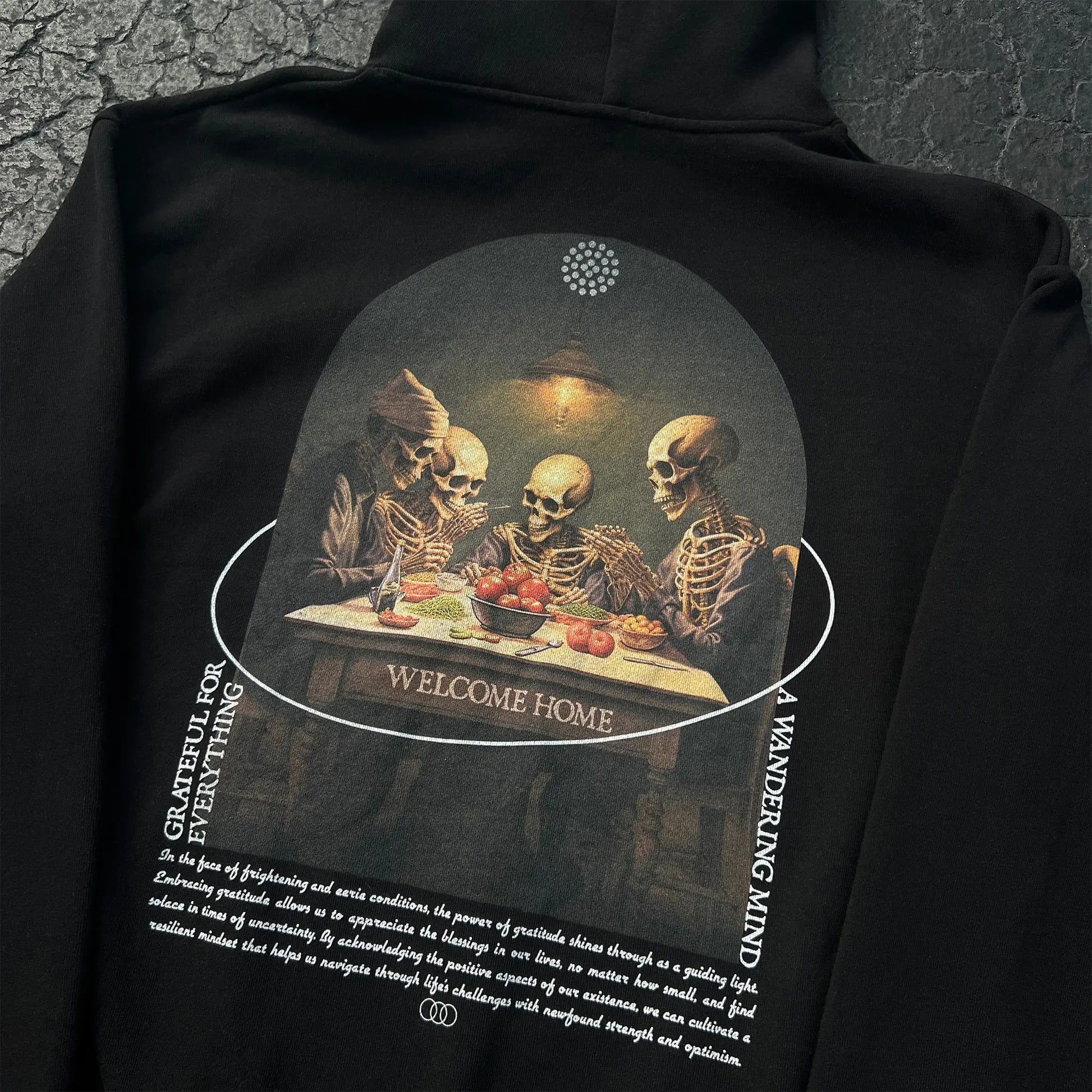A Wandering Mind Grateful for Everything hoodie in black back graphic angled view of skeletons at table, food, interior scene