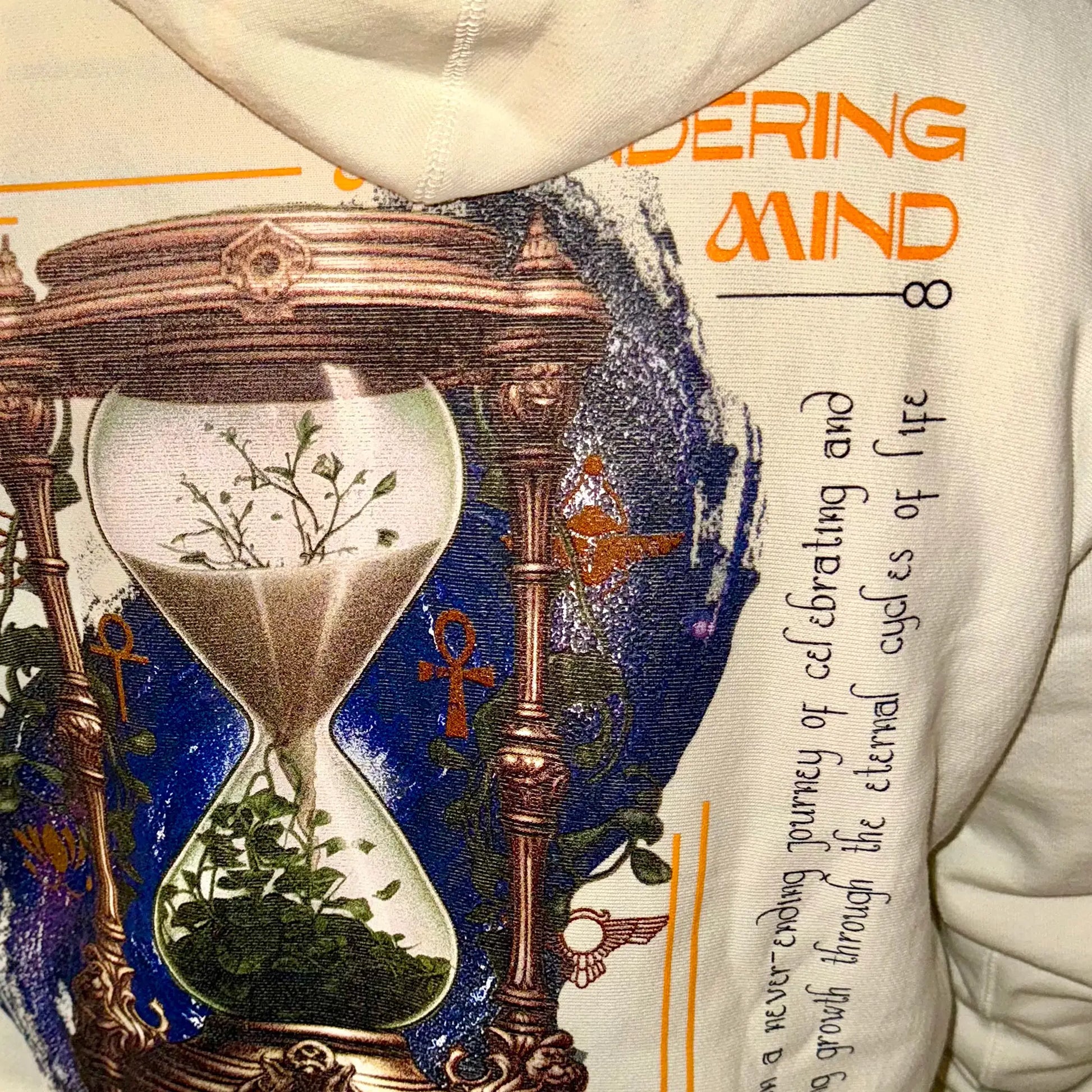 A Wandering Mind Growth and Renewal hoodie in bone back graphic view of hourglass, foliage, symbolic elements