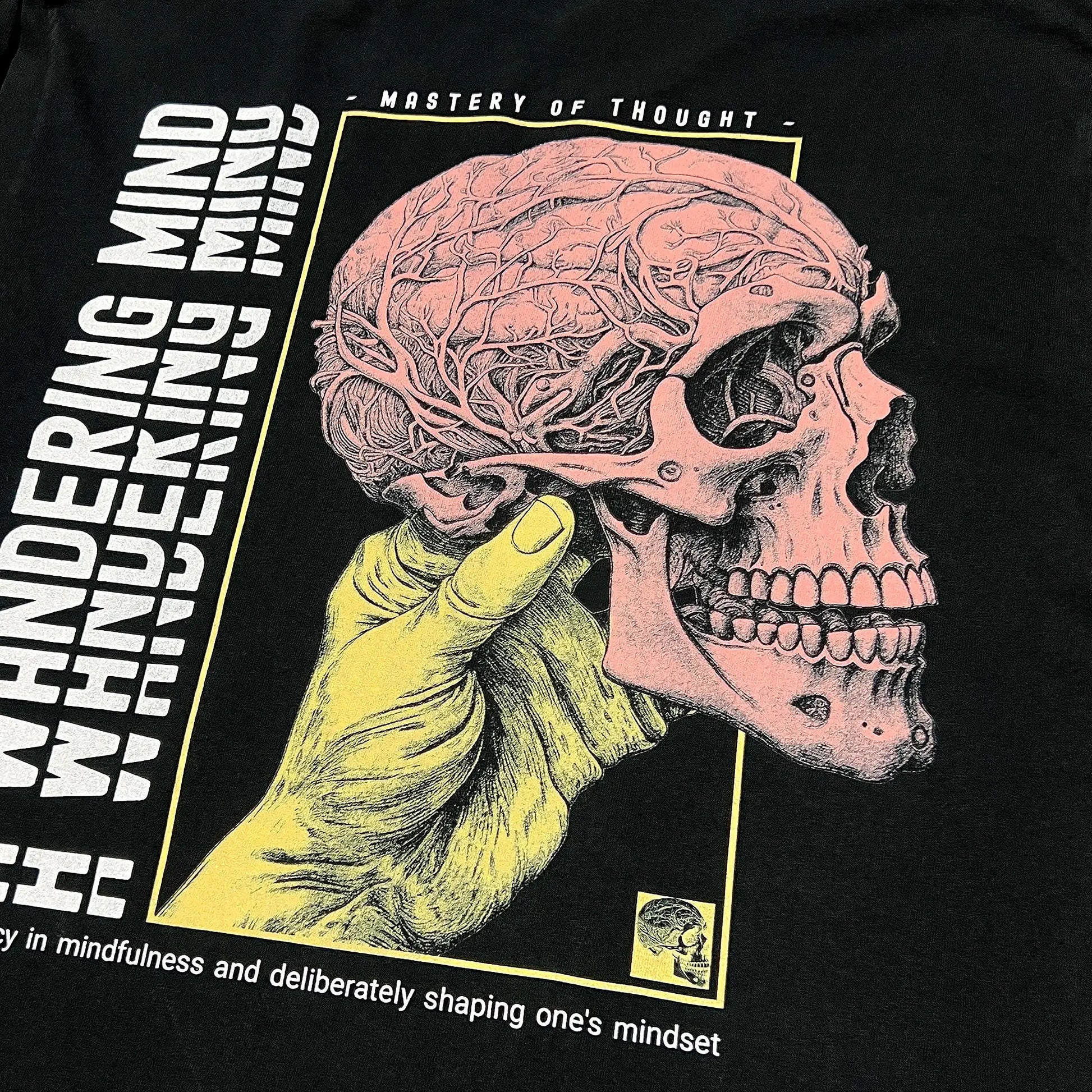 A Wandering Mind Mastery of Thought t-shirt in black back graphic featuring hand holding skull, exposed brain