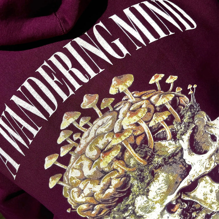 A Wandering Mind Rebirth hoodie in maroon back graphic angled view of skull, mushrooms, moss
