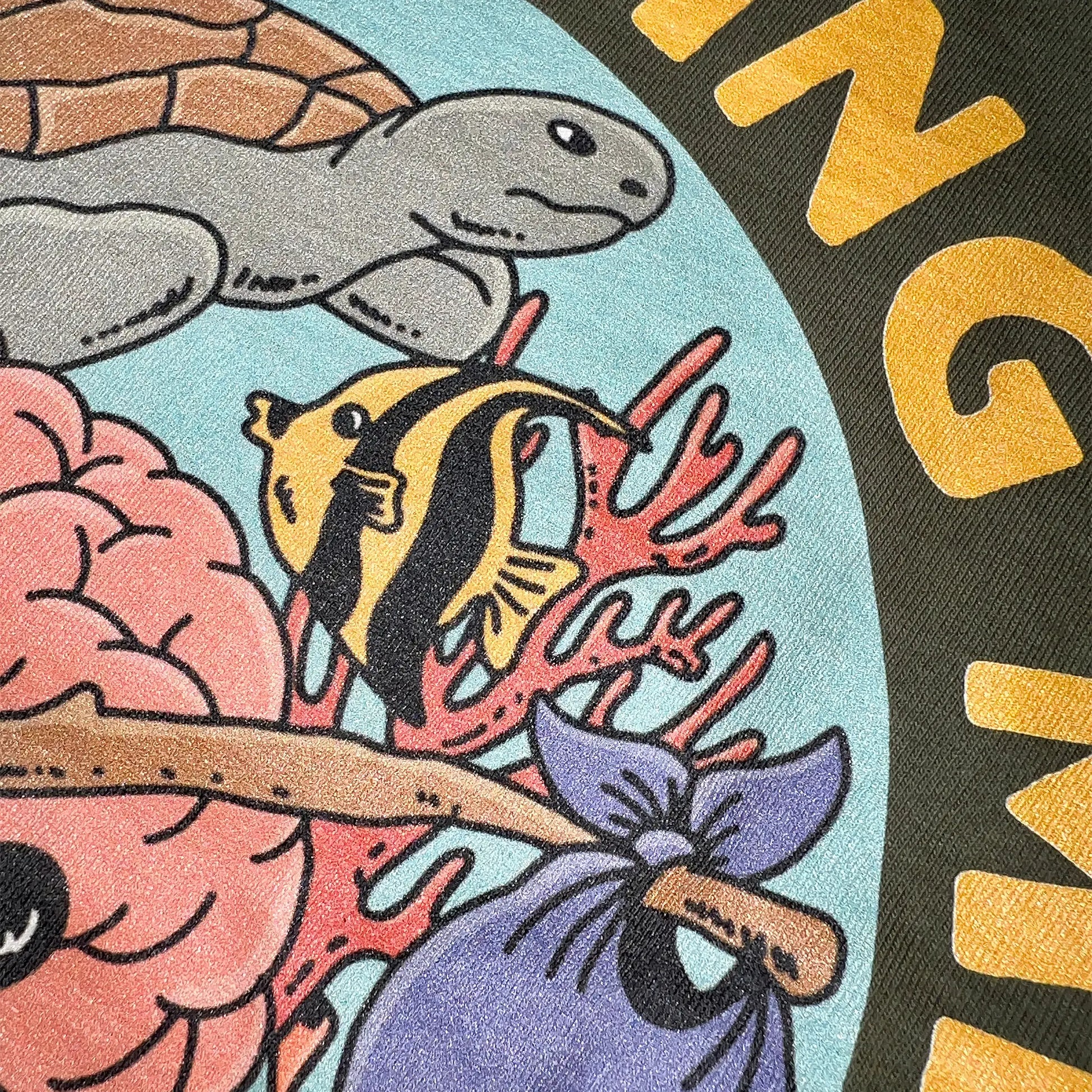 A Wandering Mind Sunken Thoughts t-shirt in olive back graphic detail showing wandering brain character, reef, sea turtle, angelfish, sea life
